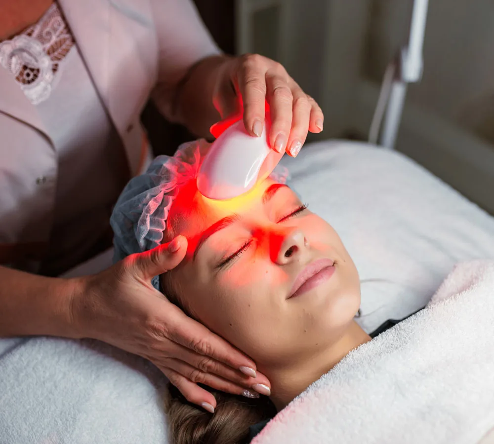 Woman relaxing during a facial treatment with a handheld light device