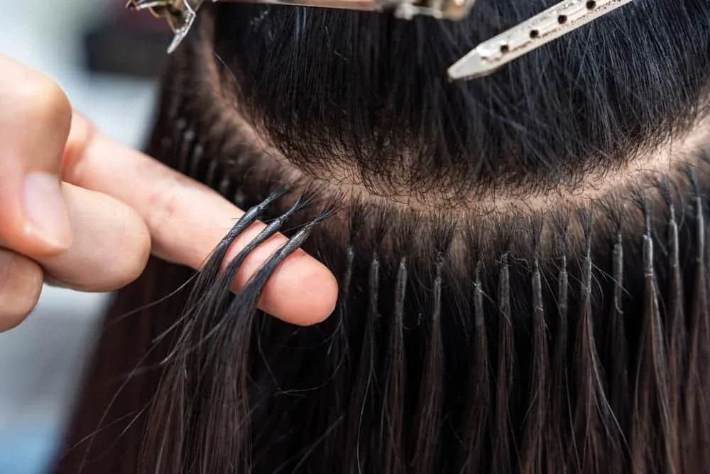 Stylist fitting hair extensions close to the roots