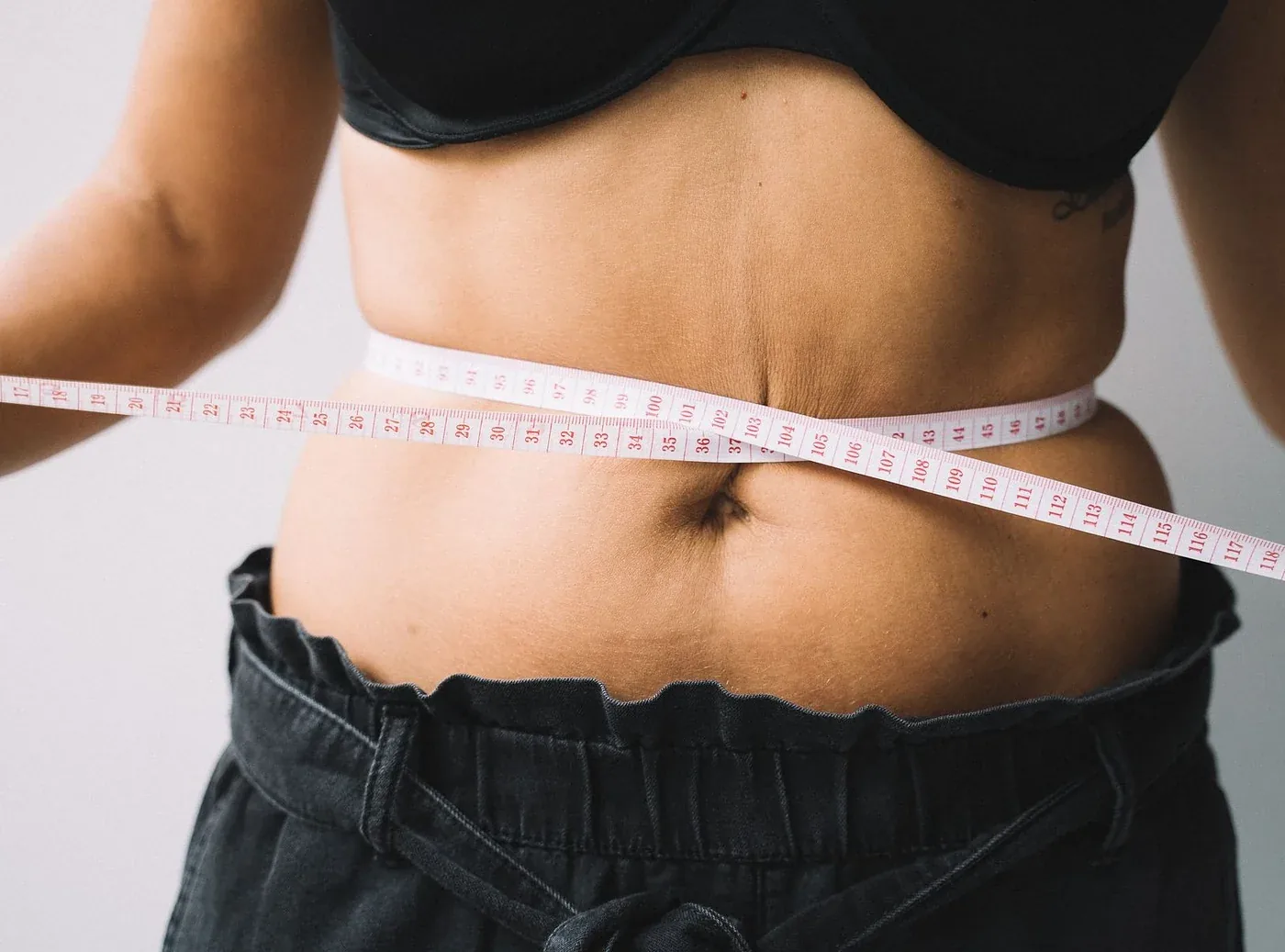 Close-up of a tape measure around a woman’s waist for inch loss treatment