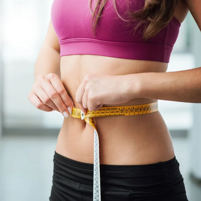 Woman measuring her slim waist with a measuring tape